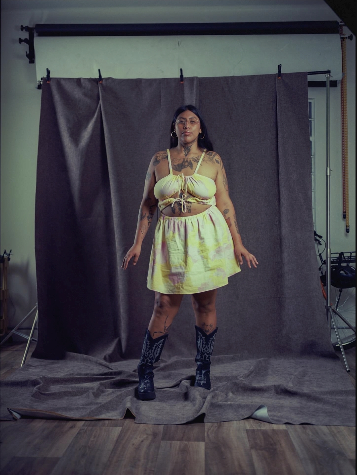 Studio backdrop with dark grey fabric drapes and a wooden floor.