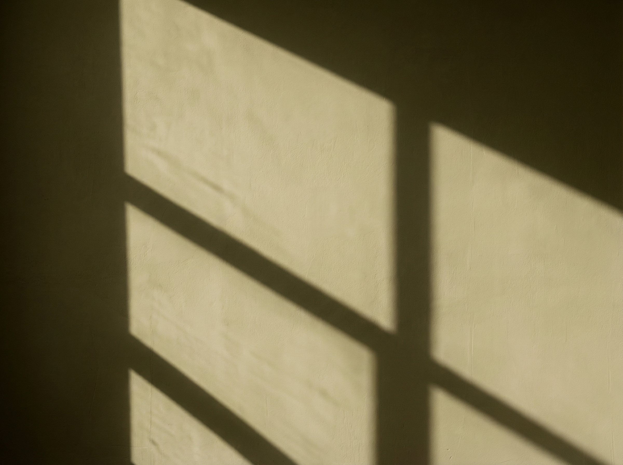 Textured interior light brown wall with geometric shadow patterns.